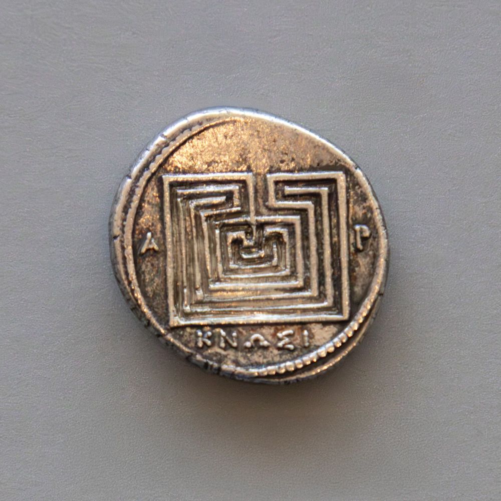 The front (obverse) of this small silver coin depicts the head of the goddess Hera facing left. The back (reverse) depicts a square labyrinth with the name of the location where it was minted, in Greek: ΚΝΩΣΙ (Knossos).

The city of Knossos drew its civic icon from the myth of the Minotaur. The monster, born to the queen of Crete, was hidden away in a labyrinth, or maze. Yearly he devoured youths and maidens until, with the help of a ball of string, the hero Theseus made his way to the center of the labyrinth. There he killed the Minotaur and used the string to find his way out of the maze. The story was so famous that anyone seeing the labyrinth on this coin knew that Knossos was its source.

Art Institute of Chicago (1922.4914)