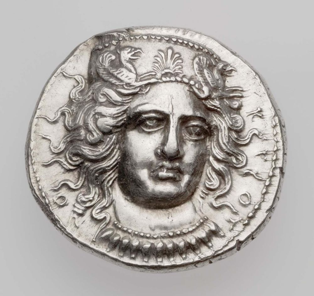 Silver stater (coin) with the beautifully molded head of Hera Lakinia facing three quarters right, wearing a high stephanos (crown or tiara) with a palmette between the foreparts of right-facing griffins; the edges of the stephanos is dotted. The goddess' hair is shown long and in thick masses of curly locks which radiate out from her face, as if alive. She wears a dotted necklace with acorn-shaped pendants.

The inscription in Greek is the name of the city: Kroton.

MFA Boston (00.89)