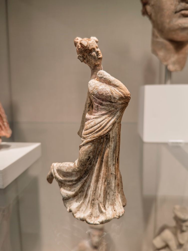 'Dance like no one is watching' ... 

Frozen while in motion, this statuette depicts a dancing woman, draped in a himation and wearing an ivy leaf wreath on her head. Her himation-wrapped right arm is folded back, her hand at her neck, her head lifted in abandon, and her right foot lifted backwards. Is it a religious dance, Dionysian, or instead linked to funerary practices? Perhaps all three. This figurine was certainly placed in a grave with the deceased person, likely a young woman. It still has traces of its original polychromy - particularly a bright pink pigment, which once covered the entire himation (cloak).

Greek, Hellenistic, South Italian, Tarentine (the Greek city-state of Taras, part of Magna Graecia, or 'Great Greece', one of the Greek colonies in Italy), ca. 3rd century BCE. 

6 × 2 7/16 × 3 3/8 in. (15.2 × 6.2 × 8.6 cm)

Met Museum, New York (11.212.20)