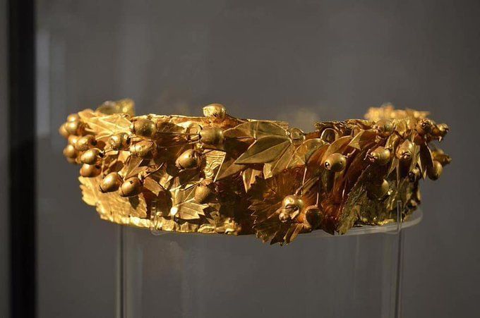 A high stephane (crown or tiara) made entirely of gold. It's wrapped in a gold myrtle branch with leaves and berries. This is a votive gift for the goddess, who wears the same crown.