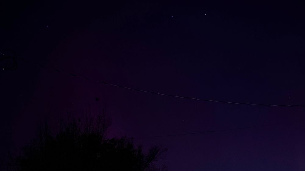 a photo of the northern lights, shown as a purple glow in the sky.