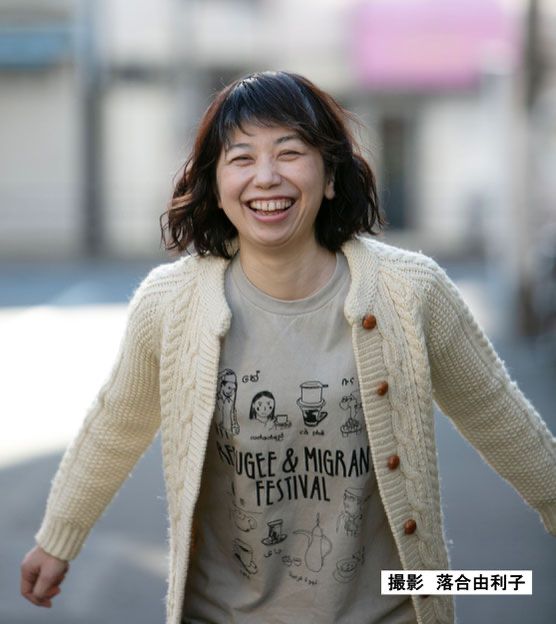 金井真紀のプロフィール写真。難民・移民フェスTシャツを着て、ゲラゲラ笑っているやつ。落合由利子さん撮影。