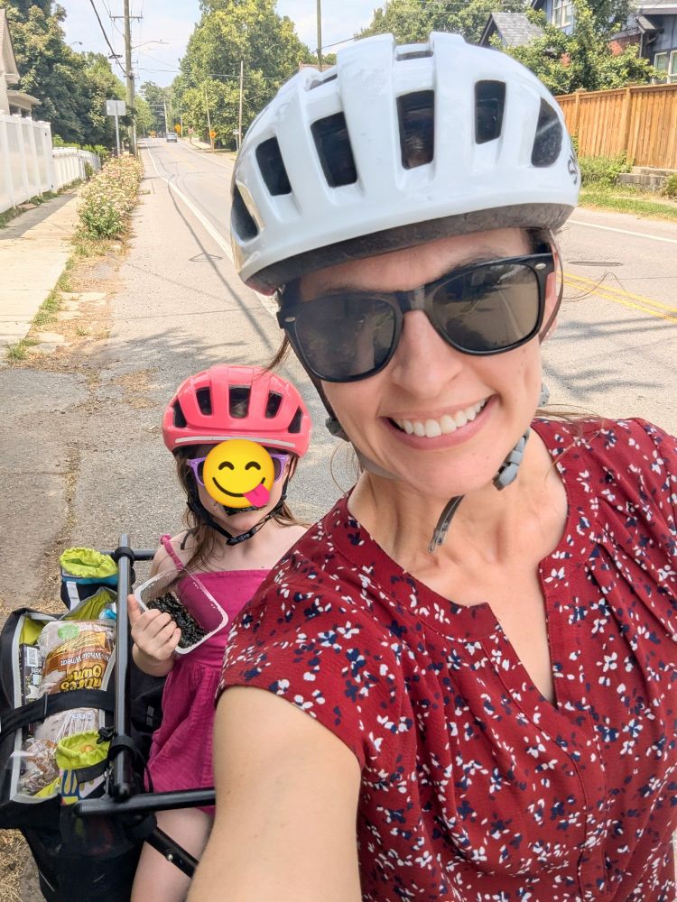 A mom and a child on a cargo bike full of groceries 