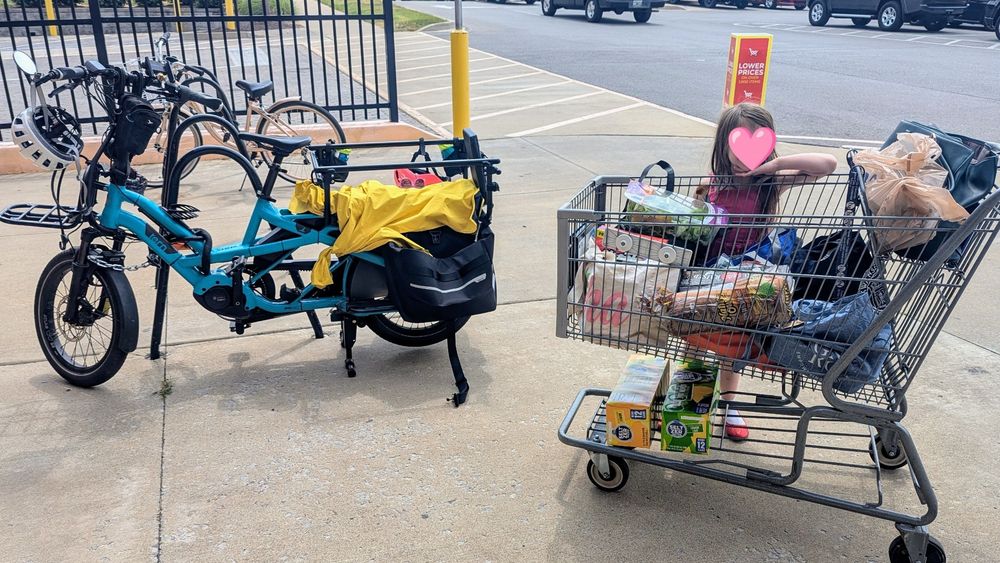 A grocery cart next to a cargo bike