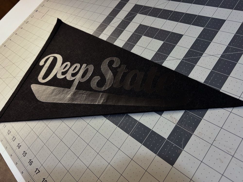 Black on black pennant that says deep state in a sports font 