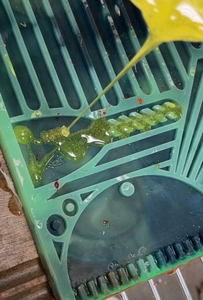 Excess yellow uncured resin being poured into a scraper shaped recess in a utility mat