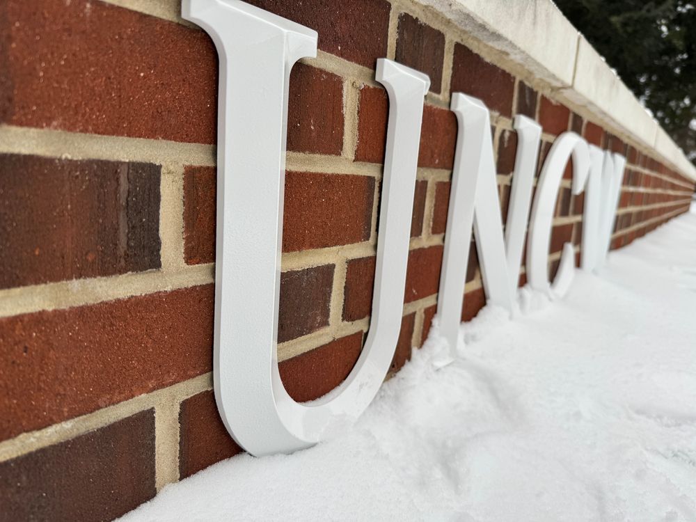 UNCW name plate on red brick with snow. 