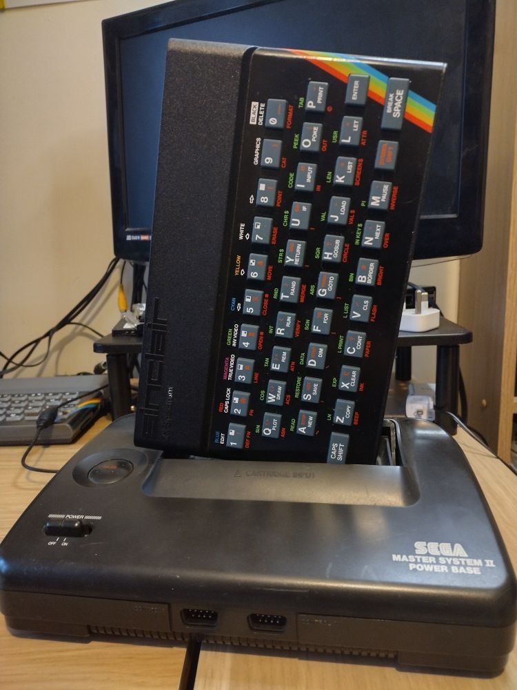 A ZX Spectrum sits in the cartridge slot of a Master System II