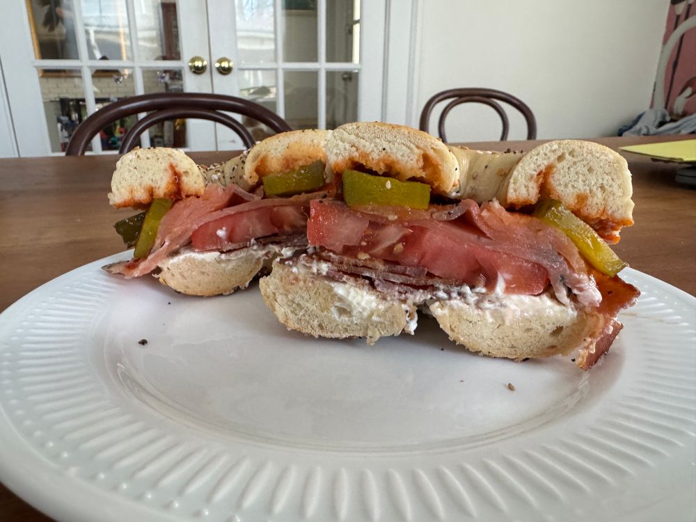 Bagel sandwich with cream cheese, bacon, smoked salmon, tomato, pickle, hot sauce 