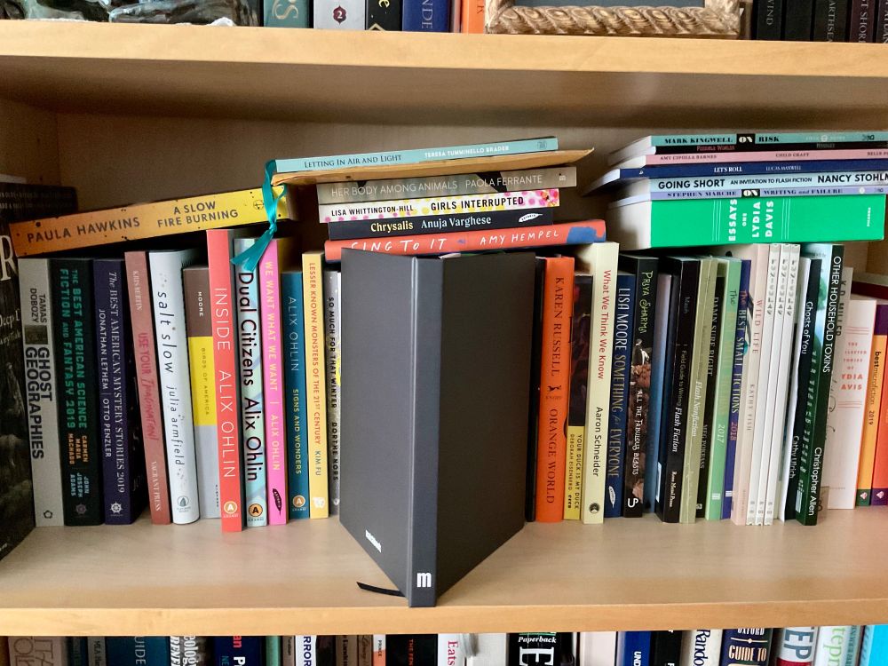 The black cover of a notebook from Matchbook Literary Magazine takes a place of pride on my stories bookshelf.