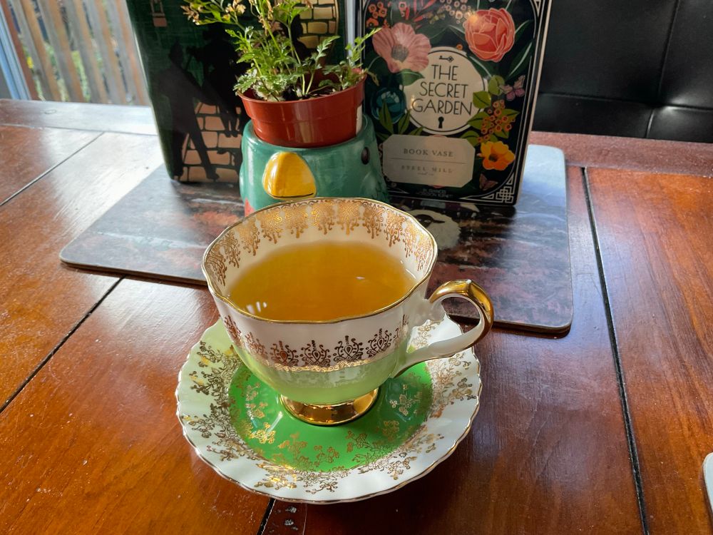 A green tea requires that I use my green (and gold) tea cup. A pair of book vases are in the background, as well as a parrot planter with a fern growing out of its head.