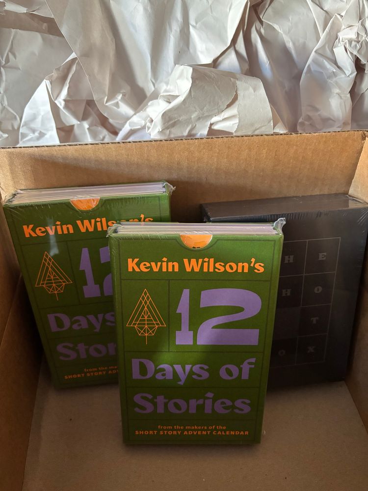 Unboxing this year’s short story advent calendar offering from Hingston & Olsen: Kevin Wilson’s 12 Days of Stories! And The Ghost Box IV.

Inside a cardboard box, there are two copies of the 12 Days of Stories. They are 12 separate stories in a green sleeve with orange and purple font.

The Ghost Box IV lurks at the back in its decadent black box. Boo!