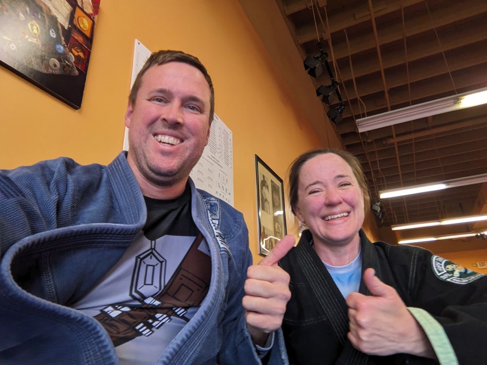 Two thumbs up from Dan and his instructor in their gis after practicing Jiujitsu.