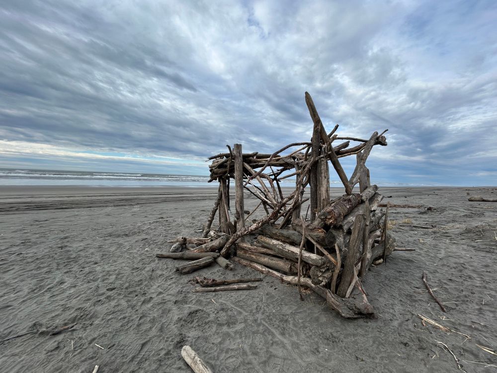 A man-made structure of driftwood on a sandy beach