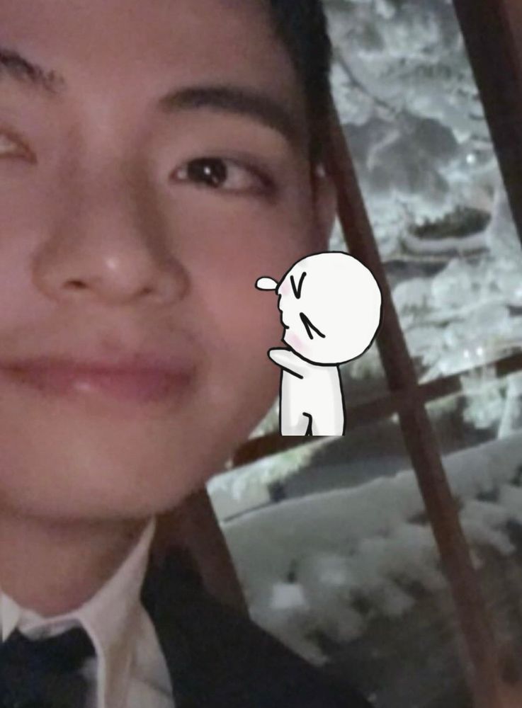 a photo of part of taehyung’s face. he is smiling and a cartoon is nibbling on his bread cheek