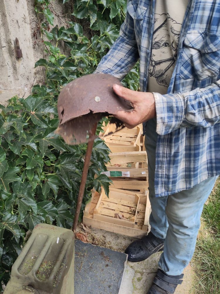 A rusty old military helmet is being held by a man