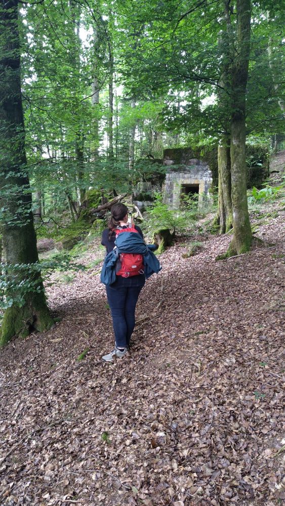 A photo of me in a forest with a hiking backpack. In the background a weathered concrete bunker is visible 