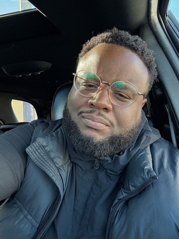 A black man stares into his phone in utter confusion. 