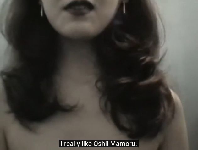 screenshot from Document Love & Pop bonus feature showing a callgirl in a bathroom stall for an interview and meetup, she is saying subtitled "I really like Oshii Mamoru."