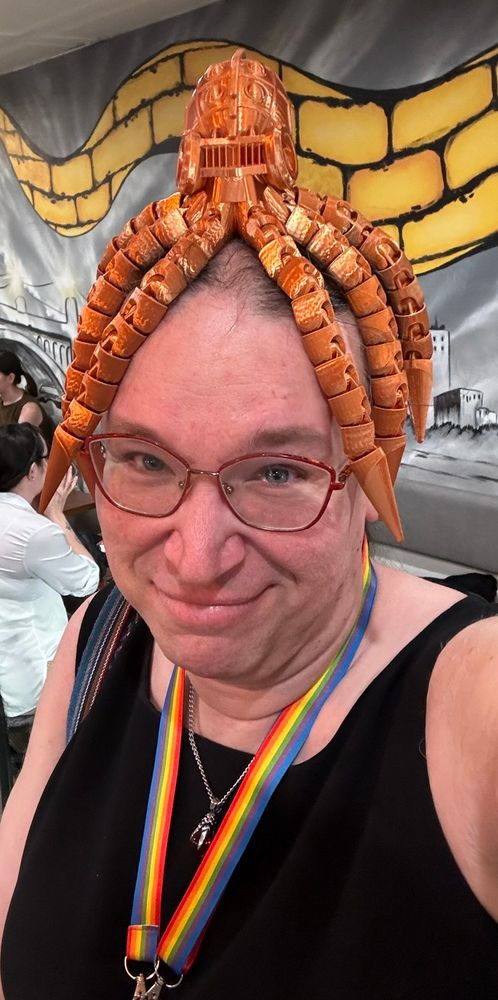 A very silly transwomen standing in line at the coffee shop with a 3d printed steampunk octopus on her head.