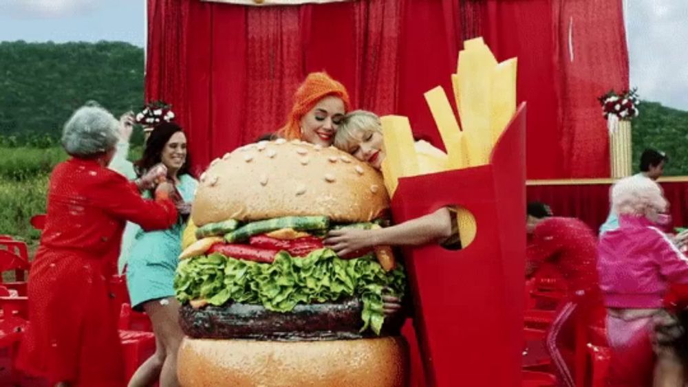 a woman in a hamburger costume is hugging another woman in a french fry costume