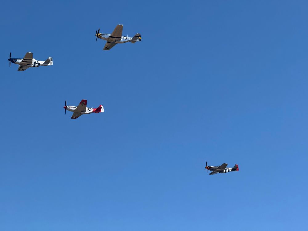 A group of 4 P51 Mustangs flying formation in a cloudless sky. 