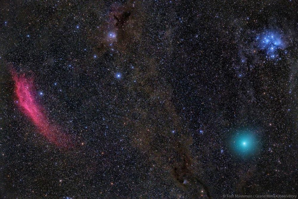 A stunning astrophotograph showcasing Comet Wirtanen in turquoise near the Pleiades star cluster.  The California Nebula (NGC 1499) in a reddish hue is visible to the left, along with dark nebulae and the faint glow of the Perseus molecular cloud. This image, captured on December 17th, highlights the comet's close approach to Earth and the vibrant colors of deep-space objects.