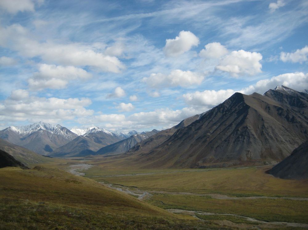 River winds through a green valley between high mountains in Alaska. Near Gates of the Arctic, that may soon be torn up for fossil fuel extraction. 