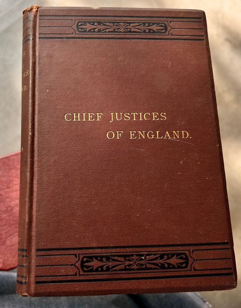 This shows the brown front of the hard cover book. In the middle and gold font is the title. “Chief Justices of England”. At the top and at the bottom of the cover are ornate borders in black.