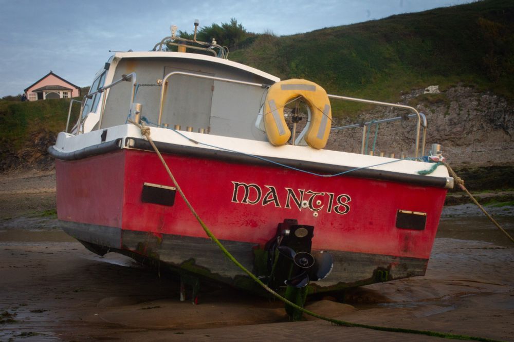 Boat anchored at low tide, named Mantis. 