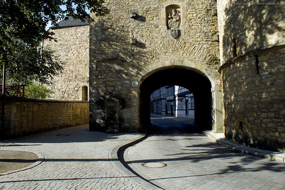 A street leading through an old stone gateway.