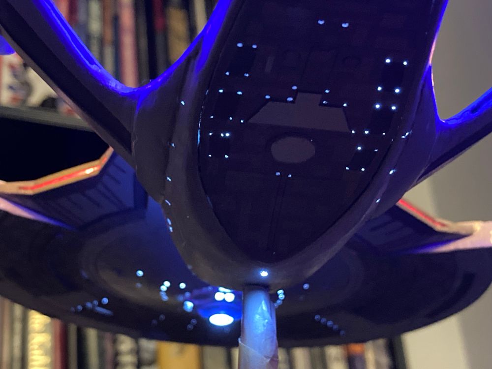 USS Enterprise G model with internal lighting viewed from beneath. Light leaks around the bottom panel are visible.