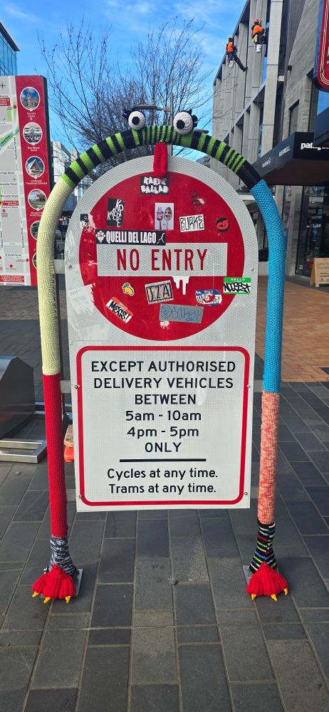 A st sign with the rod covered with a knitted Muppet