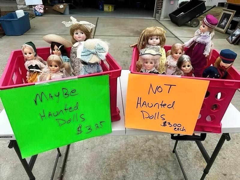Dolls for sale at a yard sale, some labeled "Maybe Haunted" for $3.25, others "Not Haunted" for $3.00.
