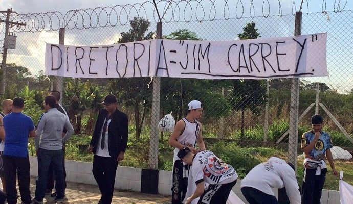 torcedores do corinthians protestando com uma faixa escrito: diretoria = "jim carrey"