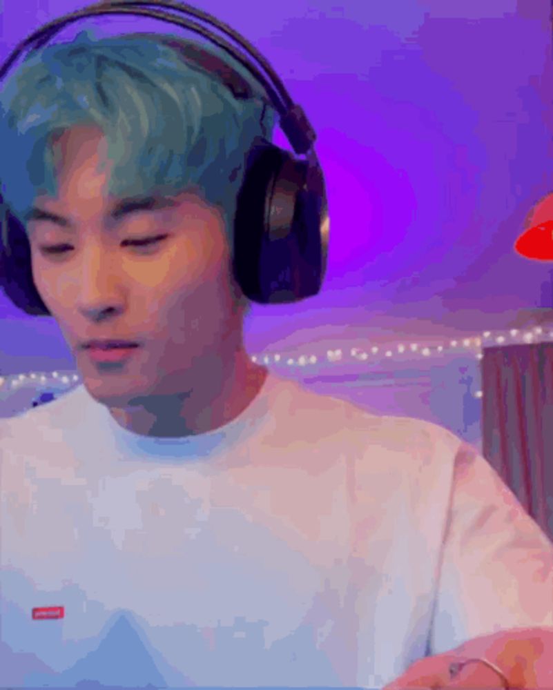 a man with blue hair wearing headphones and a white shirt .