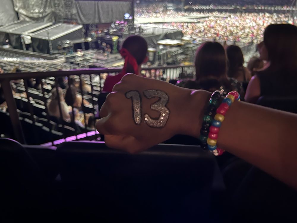 13 written on hand
eras tour stage in the background 