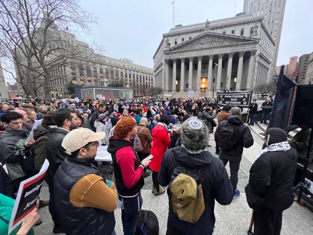 A large assembled crowd in front of a government building with stone columns