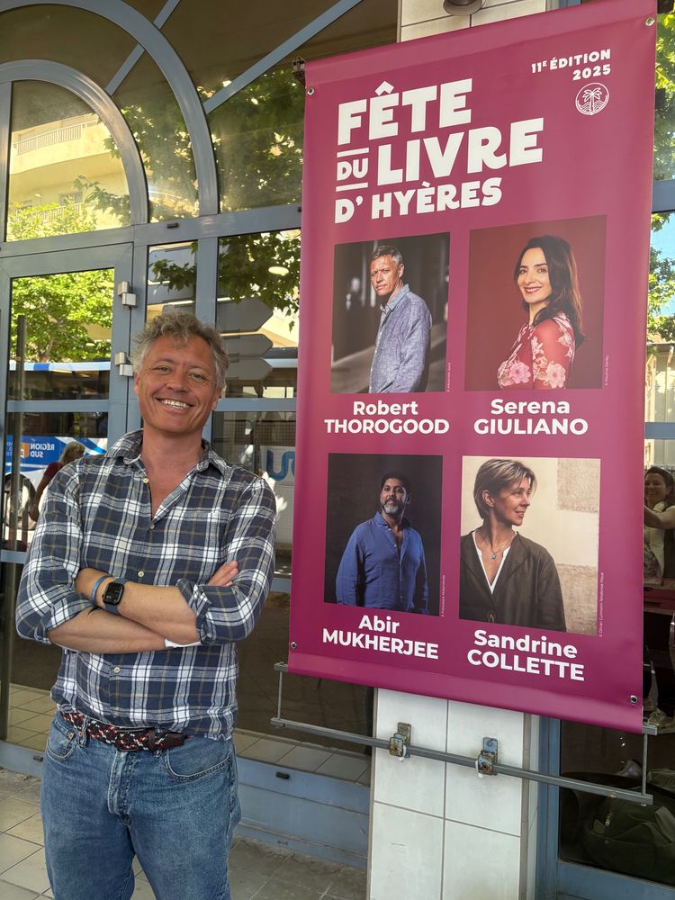 Robert stands next to a poster for the festival that has a picture of him on it