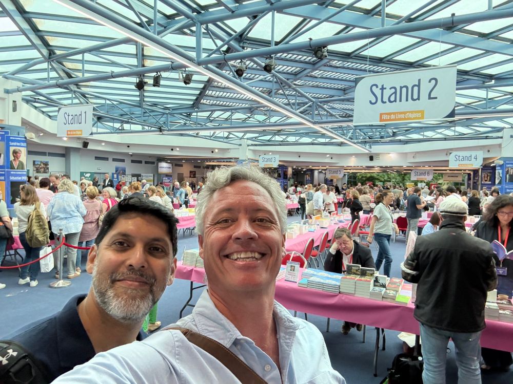 Robert and Abir smile in front of the various stands