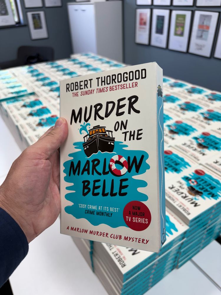 Robert holding a paperback of his latest book