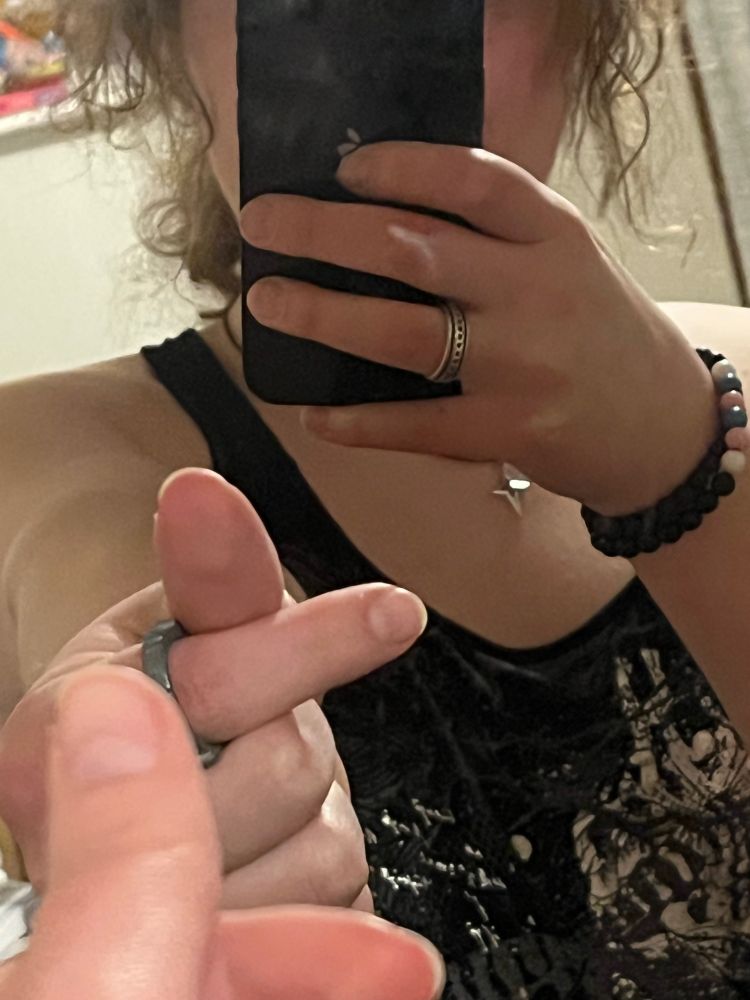 A mirror selfie of a girl whose face is obscured by her phone, holding up two fingers in the shape of a heart 