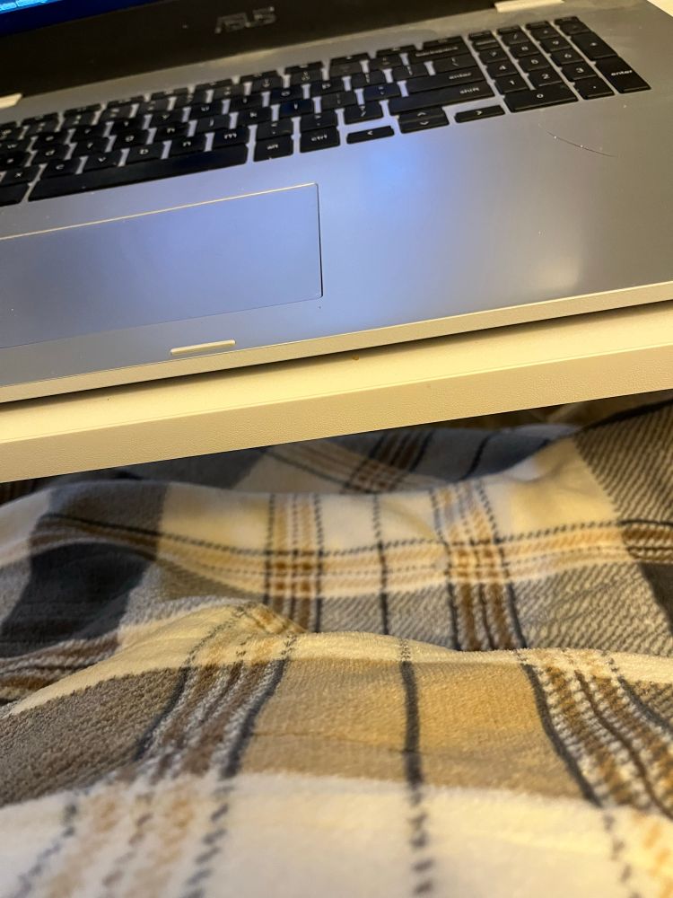 A view of my front self covered by a blanket in a brown and cream plaid. You can also see the edge of my laptop table and part of my chromebook’s keyboard.