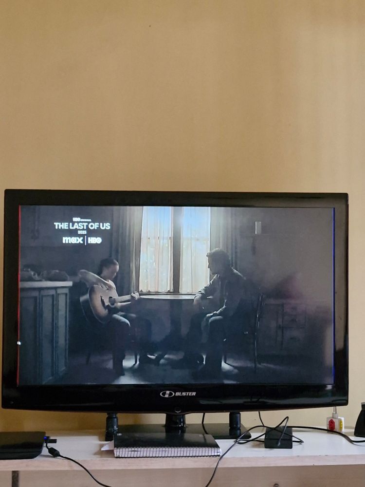 Joel e Ellie de The Last of US sentados, Ellie tocando violão para Joel