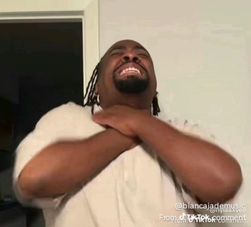 A Black man has his hands around his own neck as if he is choking himself 