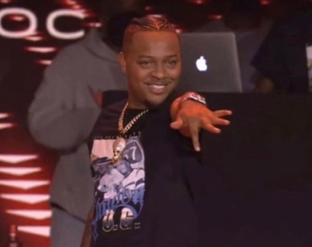 Rapper Bow Wow makes a "pushing button" gesture with his left index finger while grinning