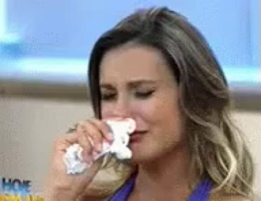 a woman is crying and holding a napkin to her nose .