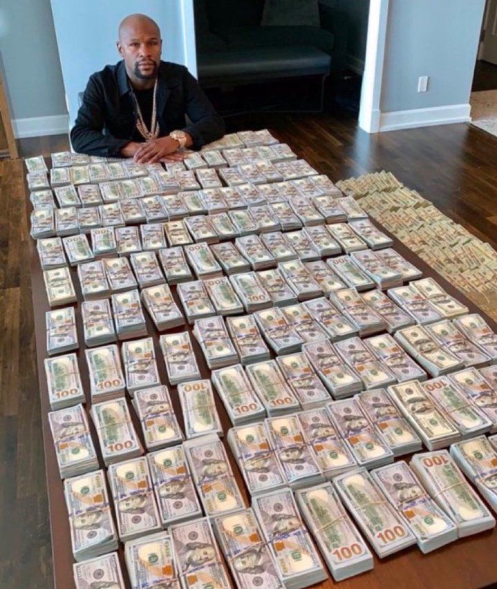 a picture of a guy with an extreme amount of 100 dollar bills on the table in front of him