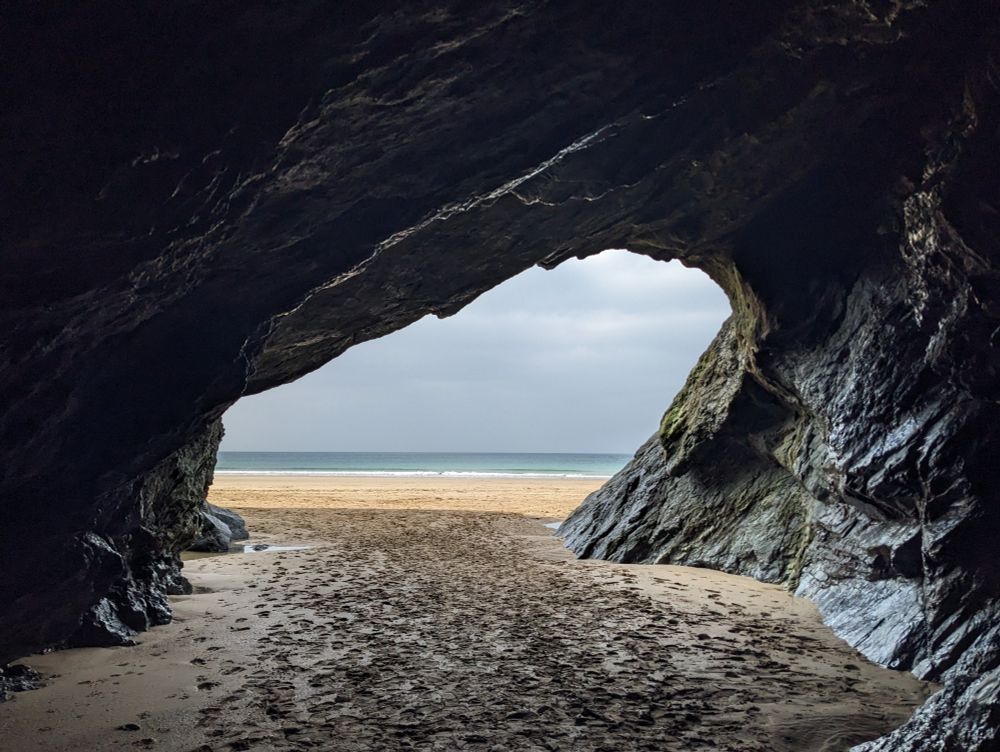 A picture taken from inside a cave looking out across the back and to the sea. 