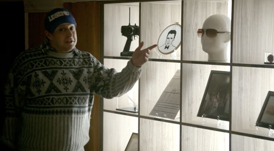 character Sean from What We Do In The Shadows TV Series showing off his collection of Ocean's 12 memorabilia